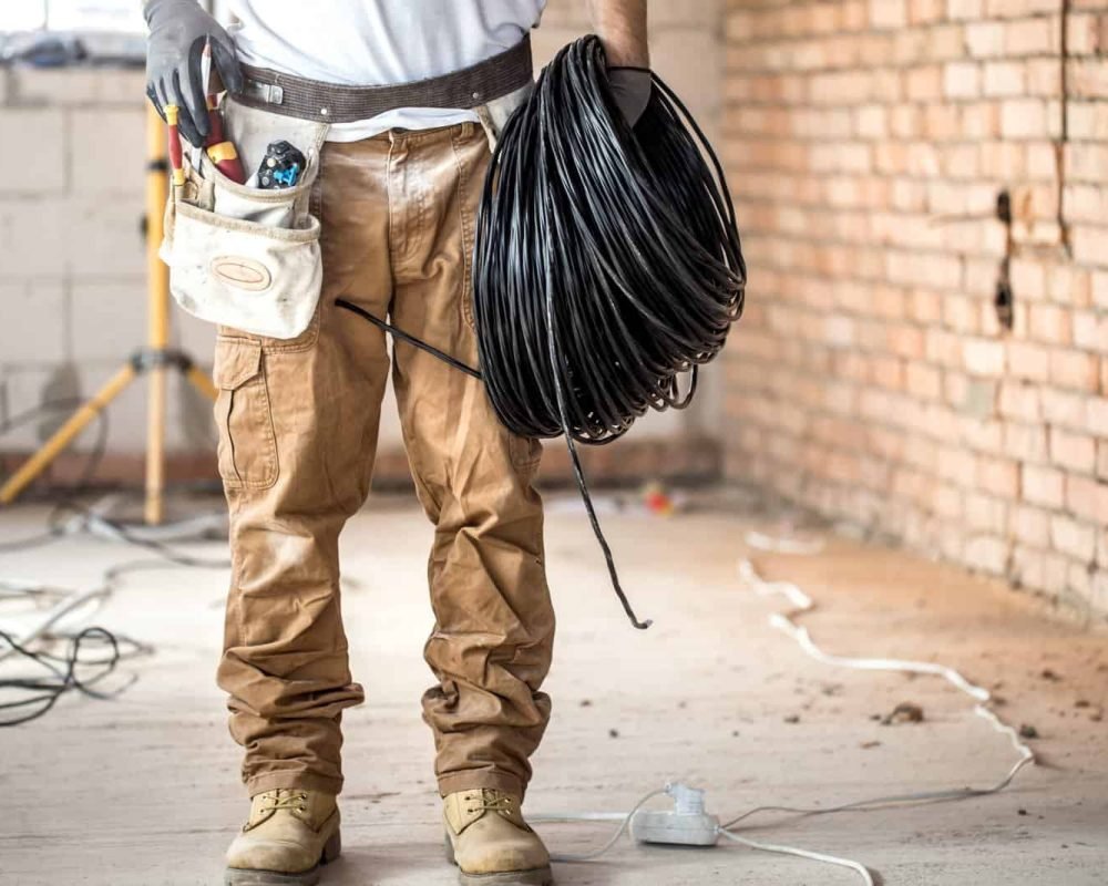 Electrician with tools, working on a construction site. Repair and handyman concept. House and house reconstruction.